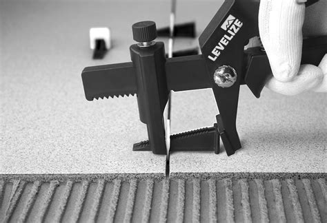 Plytelių klijavimo sistema su pritraukėjais ir pleištais